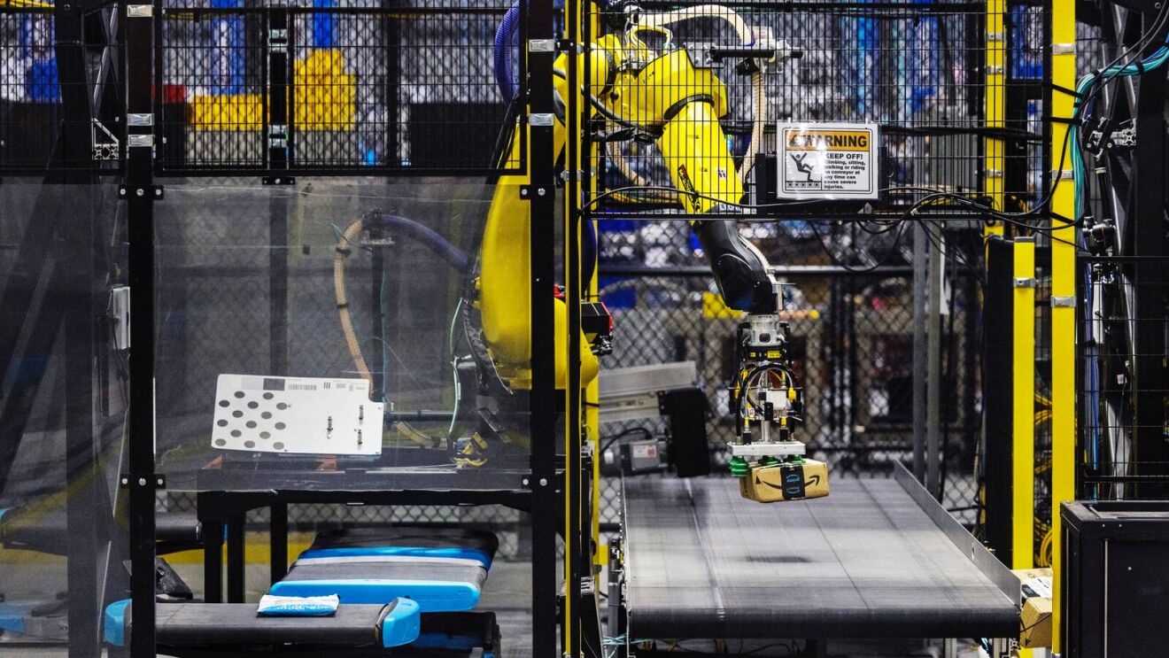 One of Amazon's robotic arm units, Robin, moves a package from a conveyor belt onto a robotic drive unit before the package is brought to the loading dock.