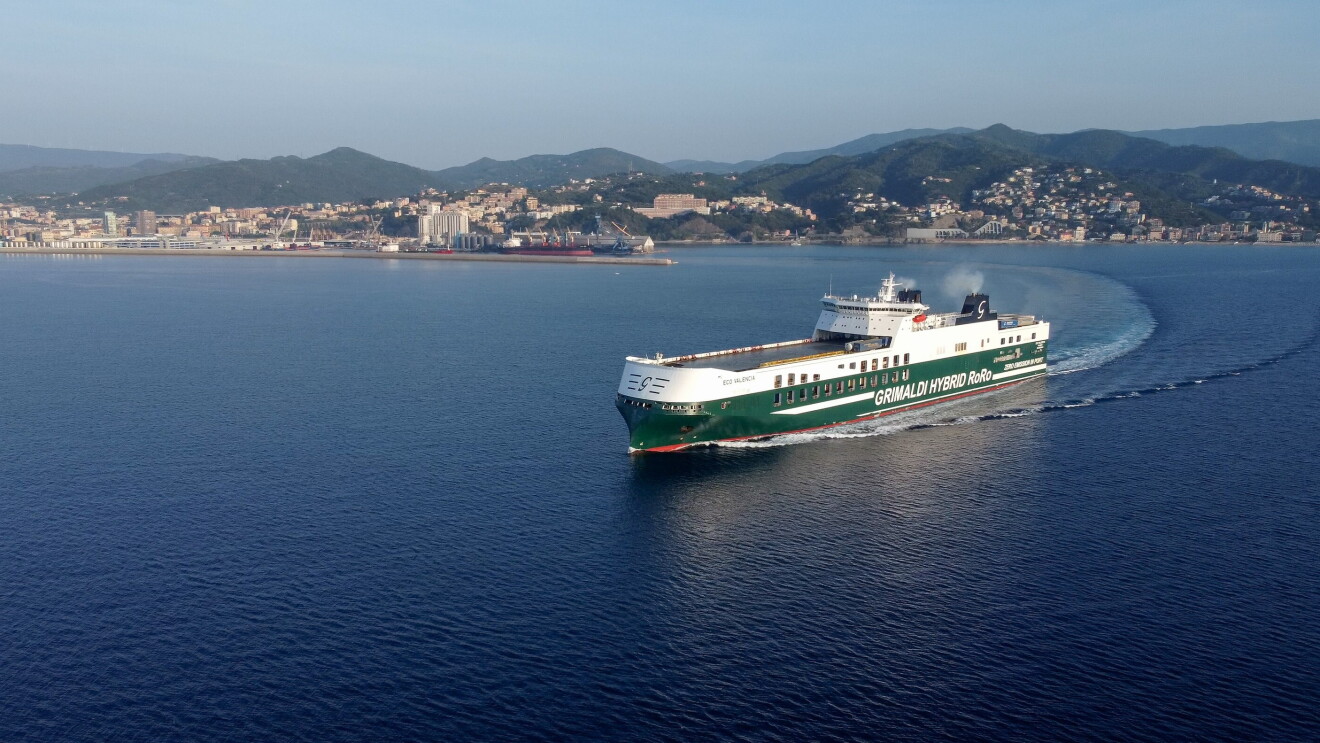 Una nave del Gruppo Grimaldi, bianca e verde, salpa sul mare, lasciandosi alle spalle il porto di Genova.