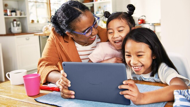 一张母亲和两个孩子微笑着看亚马逊设备的照片。