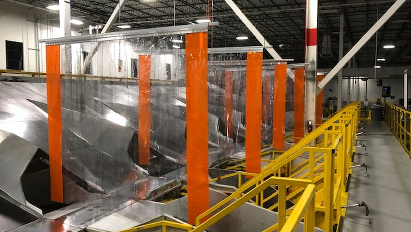 
Zobacz wnętrze centrum realizacji Amazon pokazujące fizyczne bariery między rynnami, aby zachęcić do dystansu społecznego.