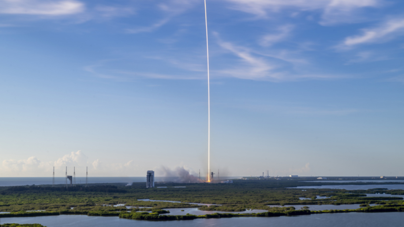 Rocket launch leaving bright trail in sky over coastal landscape