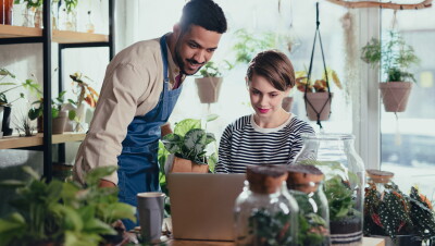 A photo of two plant shop owners working on a laptop device in a plant shop.