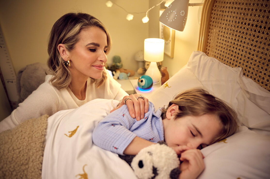 Vogue Williams puts her child to bed, with an Amazon Alexa device in the background
