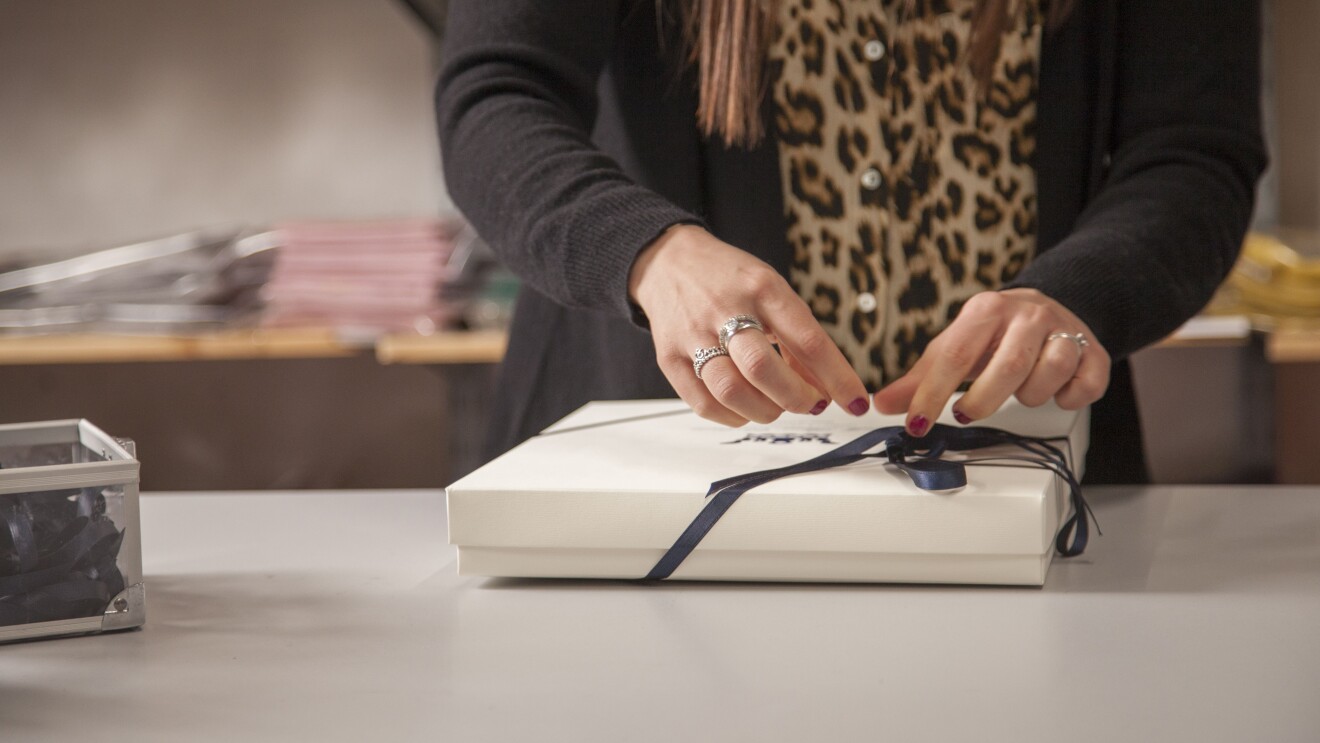 Le mani di un'impiegata Dalle Piane confezionano un ordine per un cliente con una scatola e un nastro.