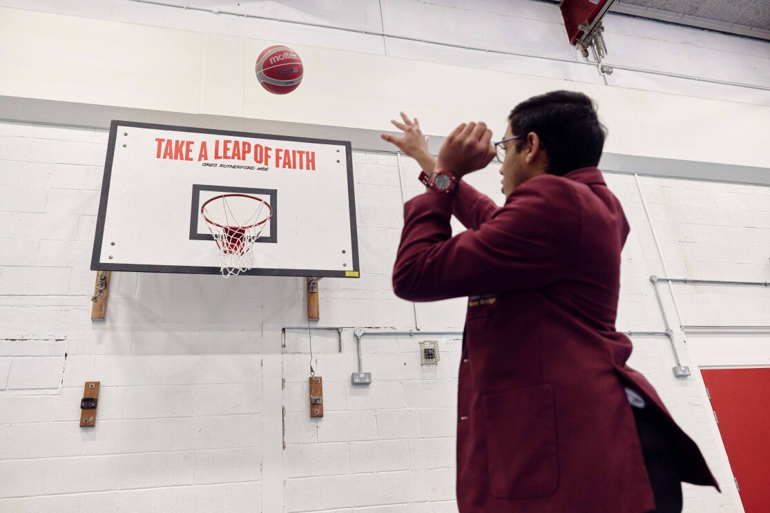 A student plays basketball in front of a Greg Rutherford quote