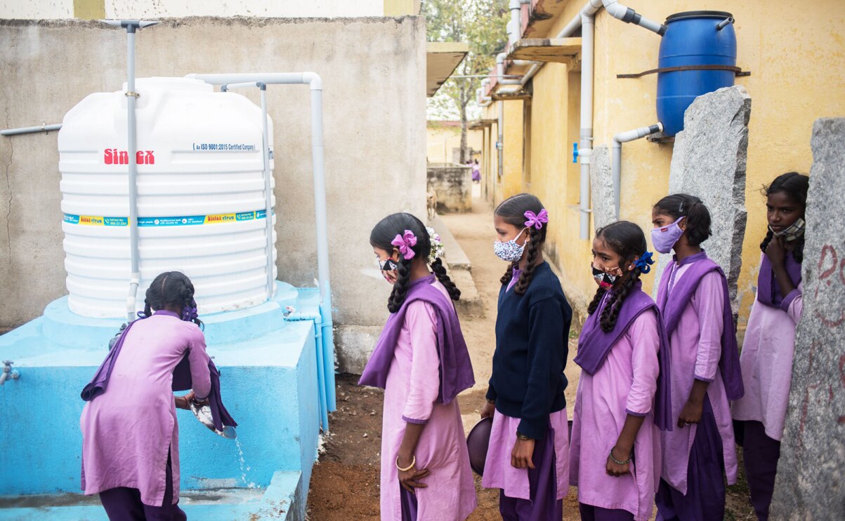 A photo of six girls in Chittoor, India standing in line at an outdoor hand-washing station