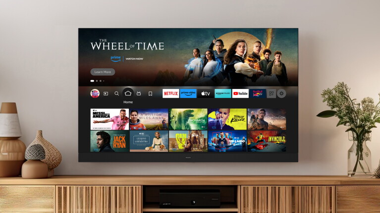 An image of a Panasonic TV mounted on the wall showing Fire TV homescreen.