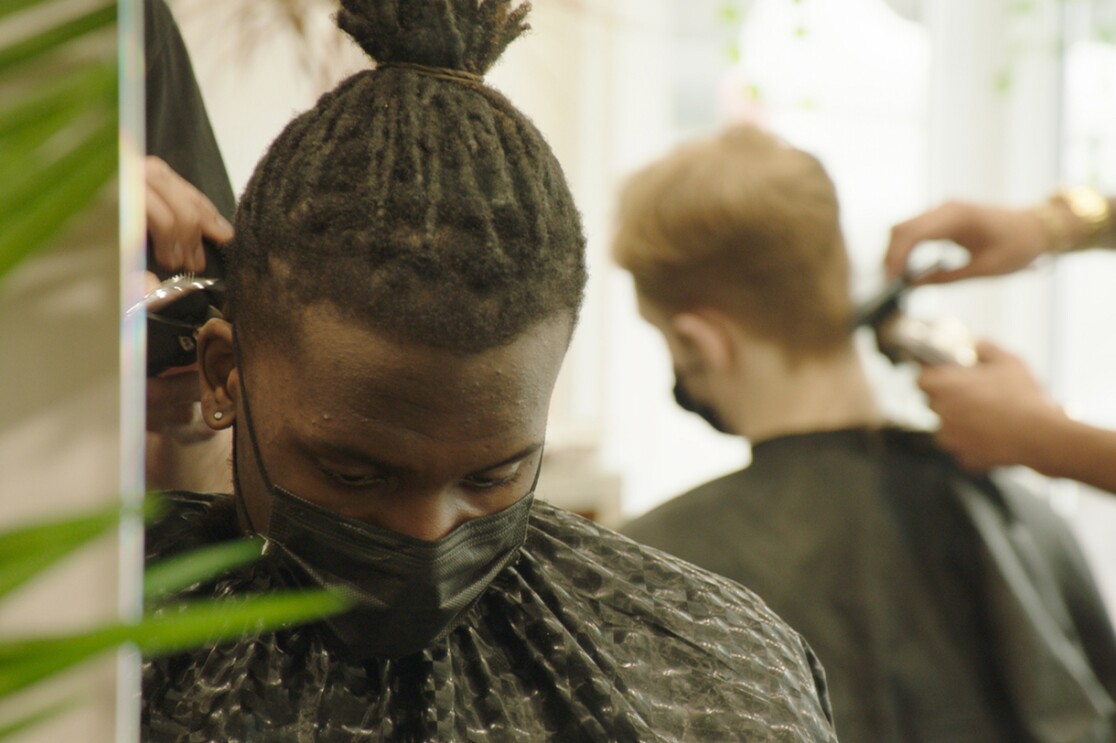 An image of a man wearing a mask while getting his hair cut.