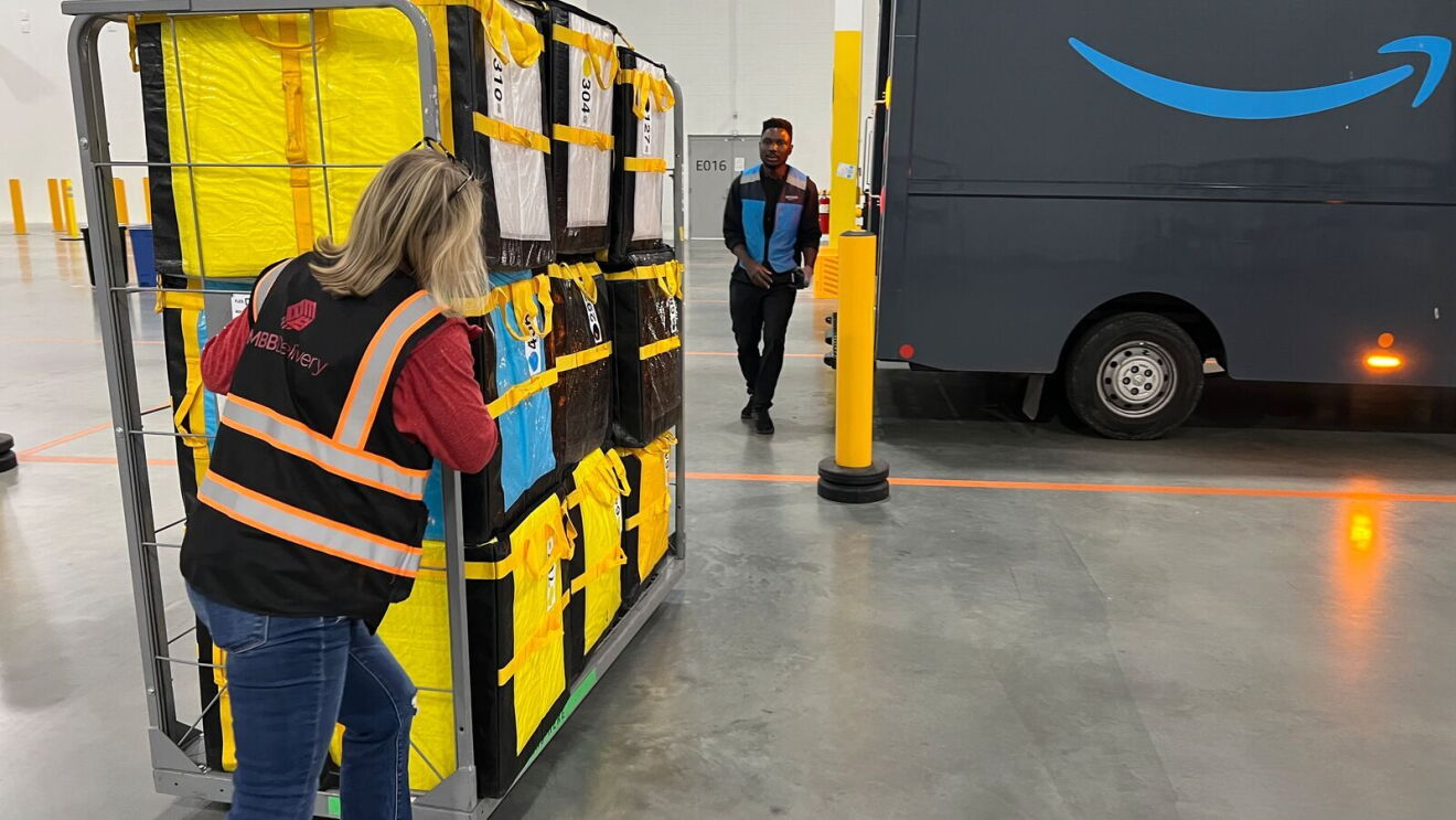 An image of a woman, an Amazon Delivery Service Partner, in a work vest standing in front of a delivery van.