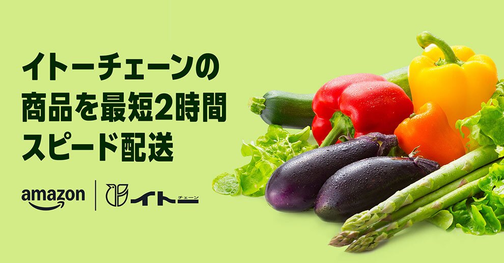 淡いグリーンの背景に、左側に黒で「イトーチェーンの商品を最短2時間スピード配送」という文字、その下にAmazonとイトーチェーンのロゴが並ぶ。右側には、表面に水滴の付いたナスと赤・黄・オレンジのパプリカを中心に、ズッキーニ、アスパラガス、レタスなどの野菜が配置されている。