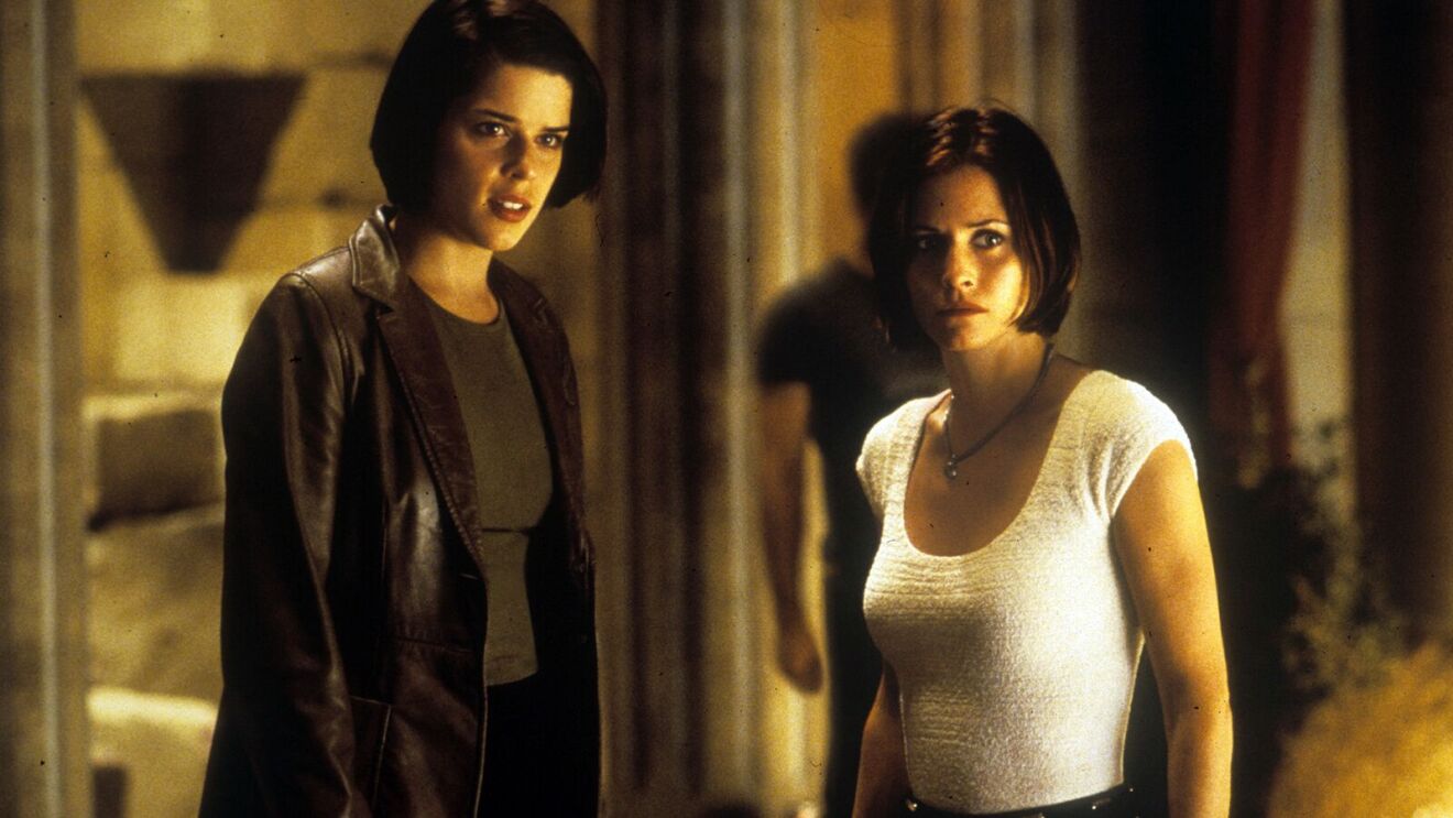 Neve Campbell and Courteney Cox intense expressions in a tense indoor setting in Scream 2