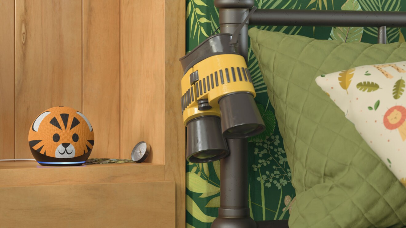 echo kids speaker in the design of a tiger sitting next to a bedframe with binoculars hung on the frame