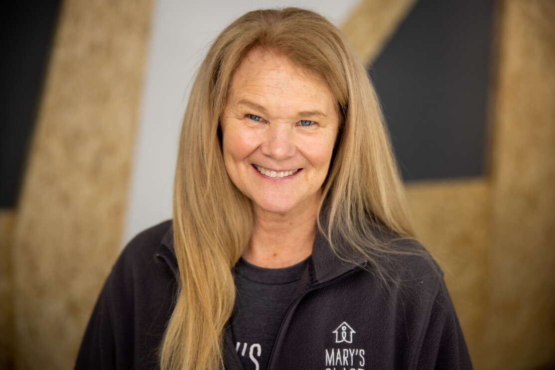 An image o a woman smiling for a headshot photo wearing a jacket with the Mary's Place logo on it.