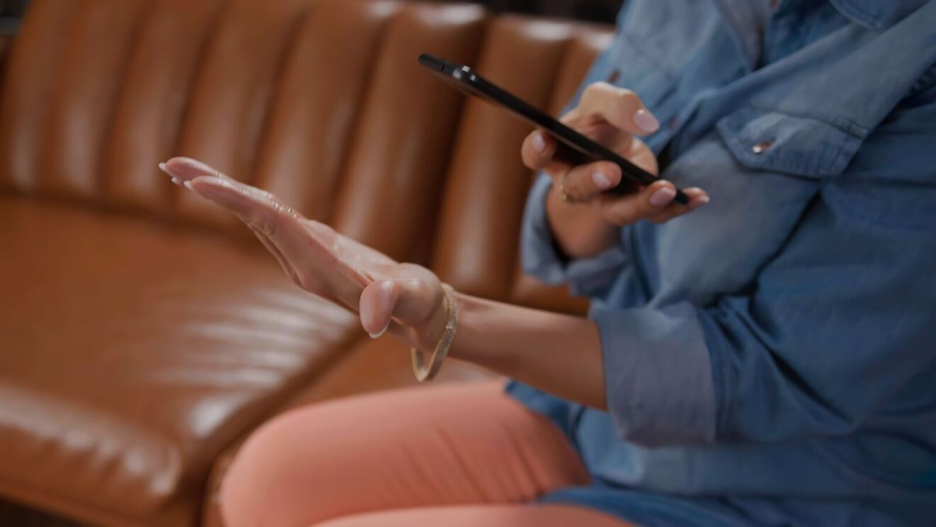 An image showing a woman's hands holding her phone and taking a photo of her hand.