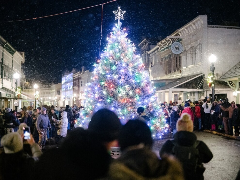 The people of Mackinac Island gather around a big decorated Christmas tree on Main Street.