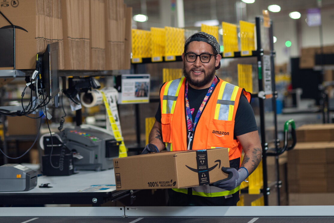 En PRIDE LEÓN un trabajador de Amazon en una estación agarrando una caja. 