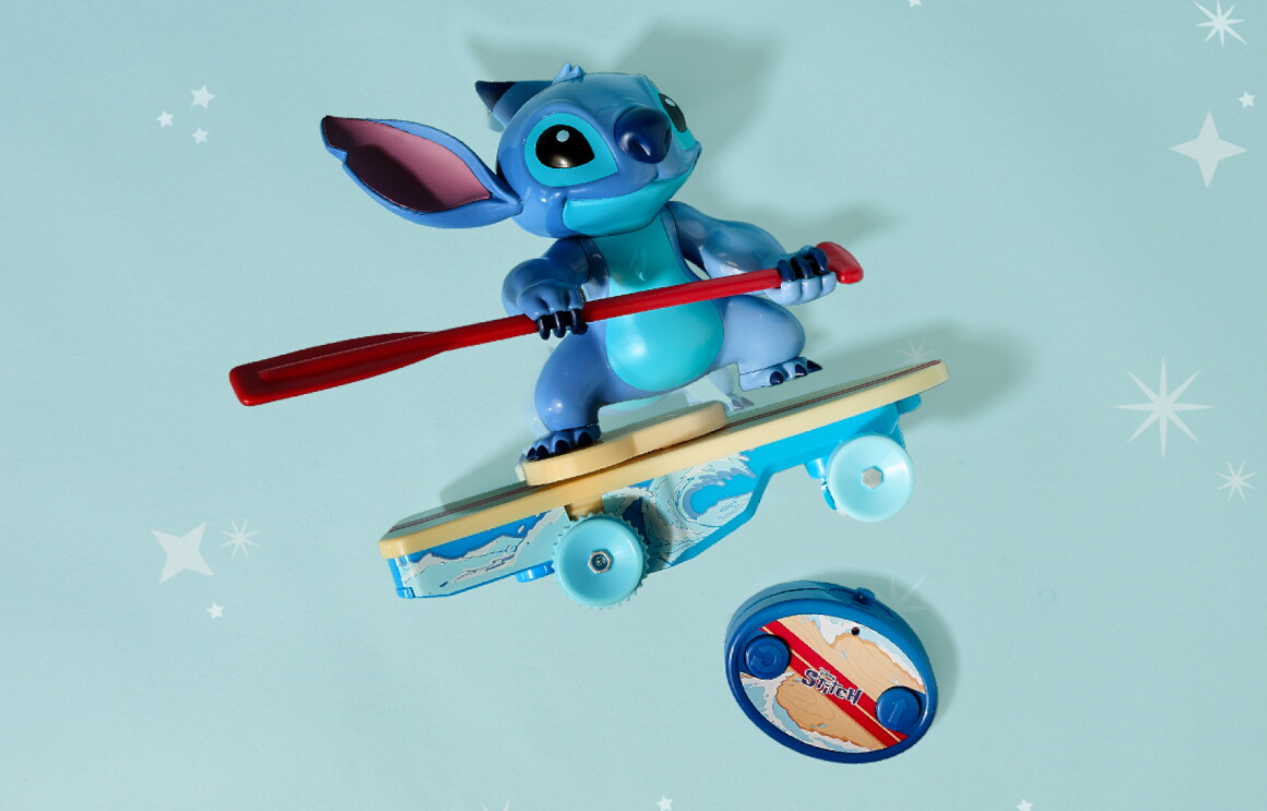 Stitch figurine surfing on a toy surfboard while holding a red paddle