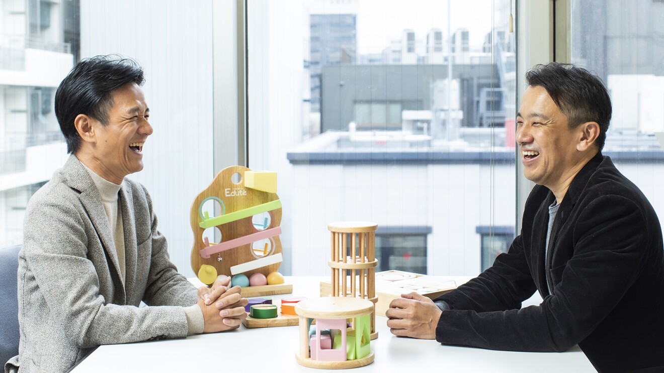 机を挟んで談笑している男性2人