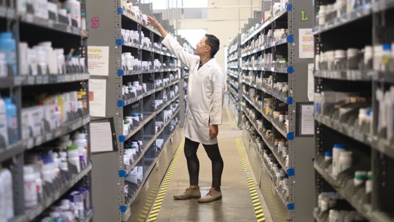 Pharmacist stocking shelves in drug store aisle
