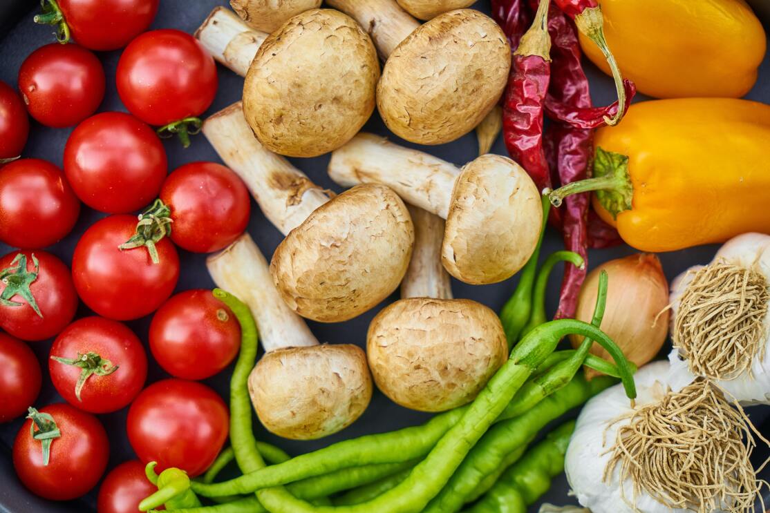 Cherry tomatoes, mushrooms, dried peppers, garlic, and green beans on a plate.