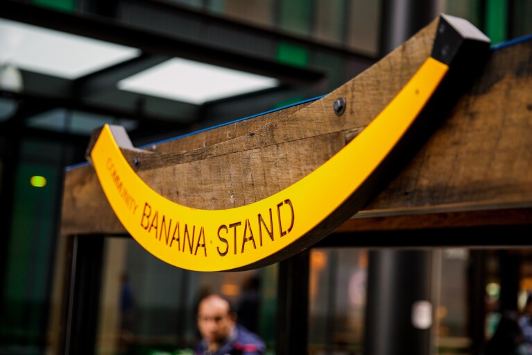 A wooden structure features a a yellow banana-shaped sign with the words "Banana Stand."