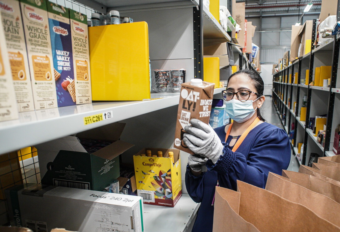 Amazon employee packing products into bags for Amazon Fresh 