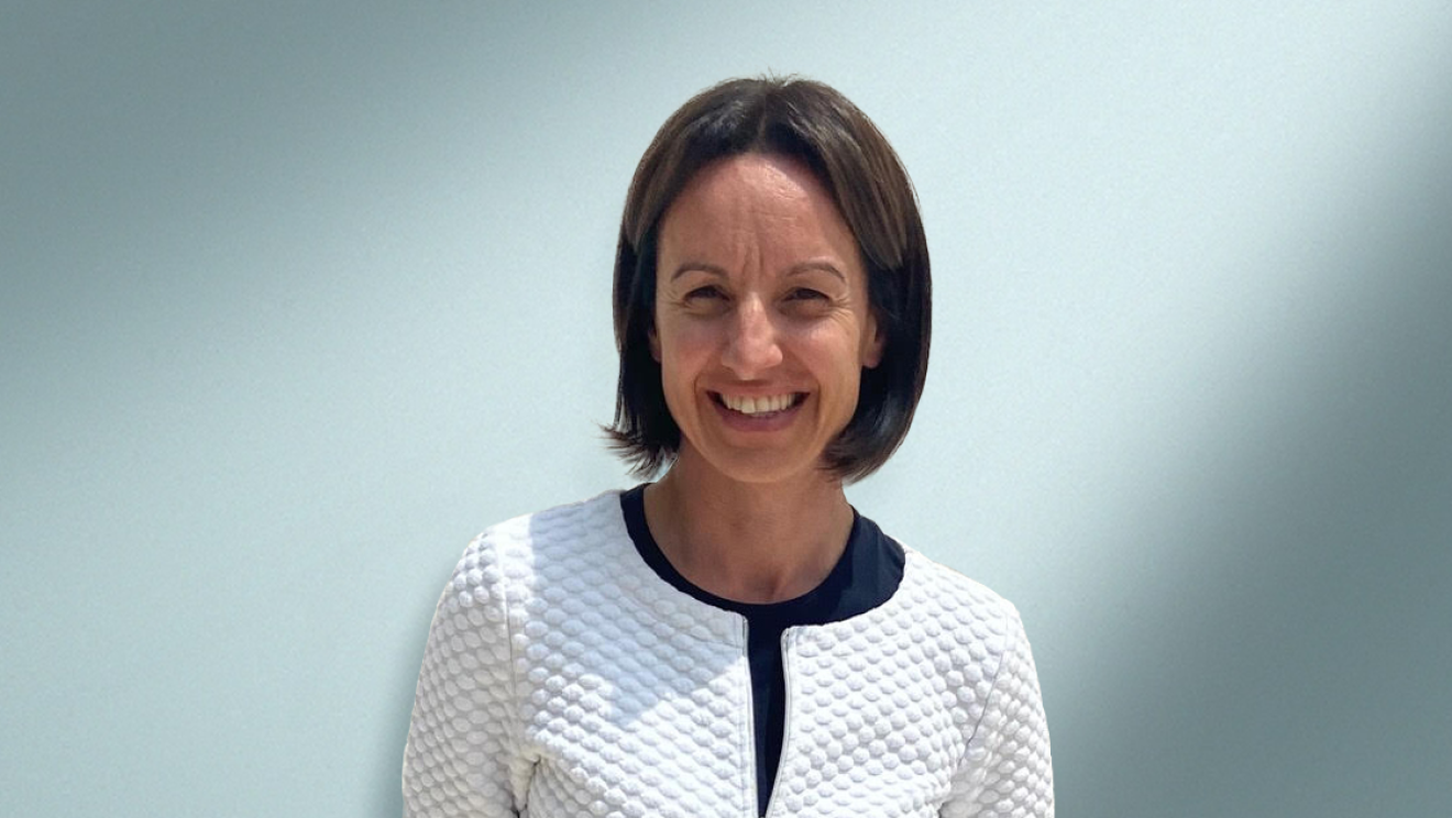 Primo piano di Sara Bernardi. La donna ha i capelli corti, indossa una giacca bianco ottico con una zip. Ha le braccia dietro la schiena.