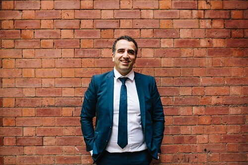 Ali Nowroozi, Founder of Masumi, standing in front of a brick wall.