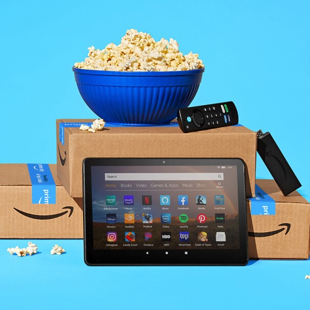 An image of a bucket of popcorn sitting atop stacked Amazon boxes. In front of the boxes is a tablet and there is a goldfish in a bowl next to all of it.