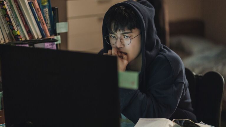 K-dramas on Prime Video: Student in hoodie focused intently on laptop screen