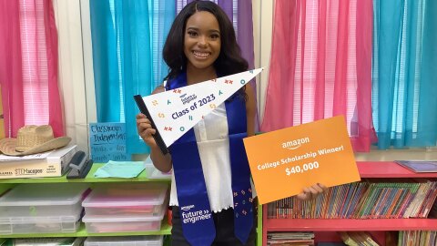 An image of Micah Hill, a 2023 Amazon Future Engineer Scholarship recipient, holding out a sign that reads "Amazon College Scholarship Winner."