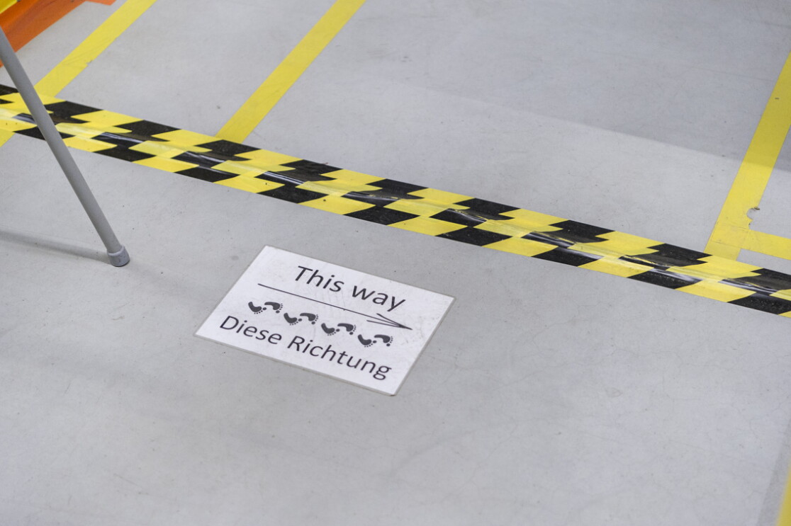 Auf dem Boden einer Lagerhalle wurde ein Schild mit der Aufschrift "This way - diese Richtung" angebracht.