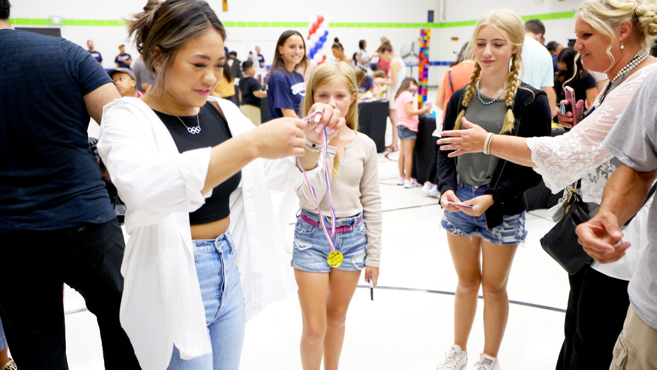 Suni Lee poses with students at an elementary school.