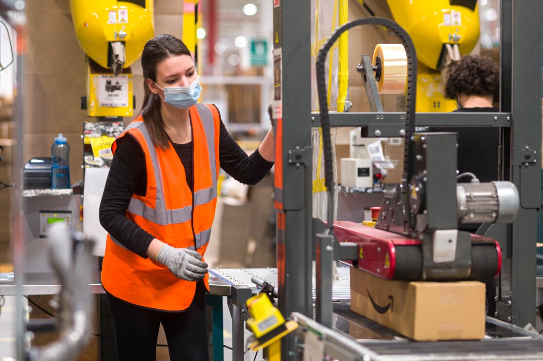 Amazon employee in mask and gloves using tape machine