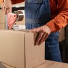 Worker sealing cardboard box with packing tape in warehouse
