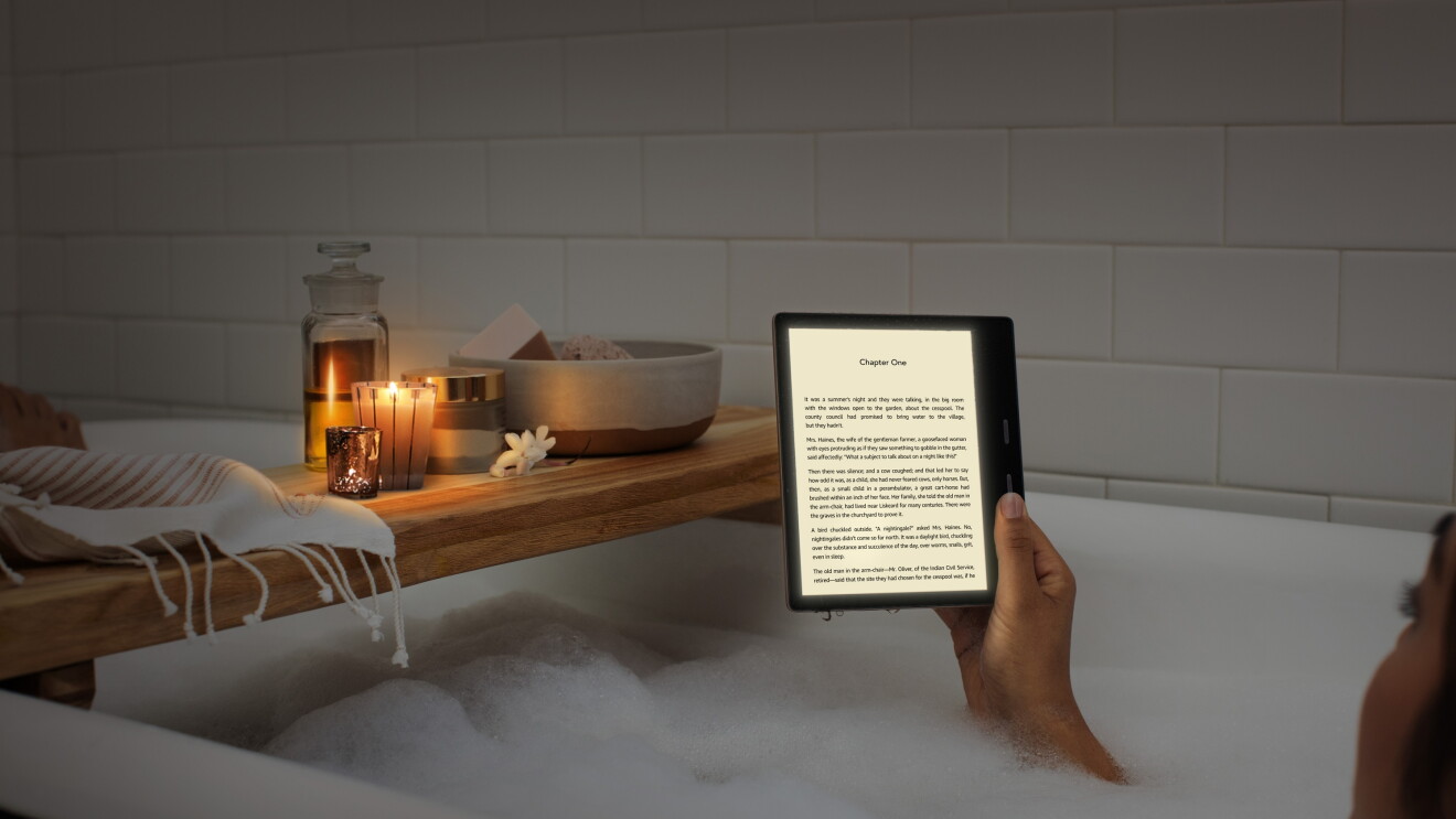 A woman reading an all-new Kindle Oasis in the bath by candle light