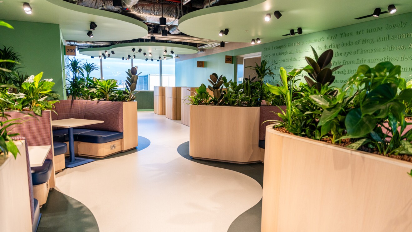 Modern green office space with plant-filled planters and curved seating areas