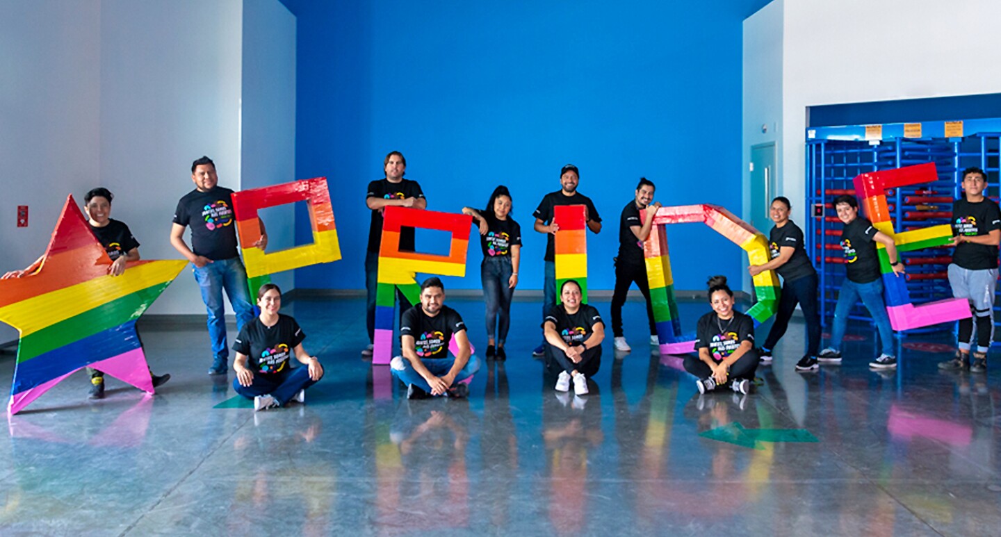 Una imagen de varios empleados de Amazon sosteniendo palabras coloridas que leen "Pride".