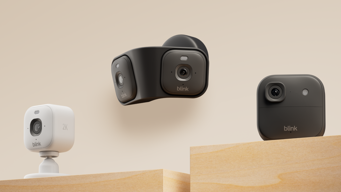 Three Blink security cameras on wooden platforms against beige background
