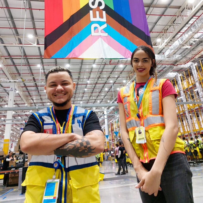 Cauê Melo e Davinna Albuquerque, funcionários da Amazon, posam em frente à bandeira Respeito