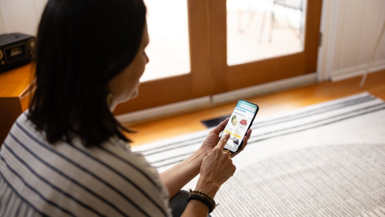 Woman shopping for groceries on Amazon app on smartphone while sitting at home