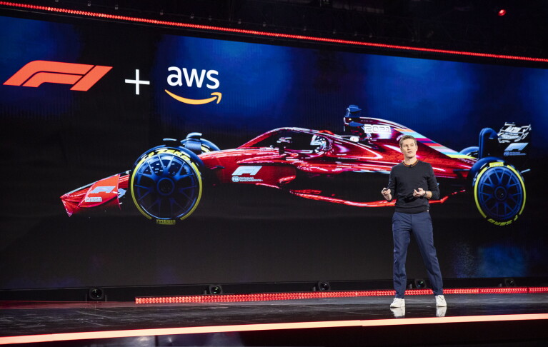 Rob Smedley, Formula 1 engineer standing on stage at the AWS re:Invent 2019 event. He is in front of a large screen with a Formula 1 car on it. 