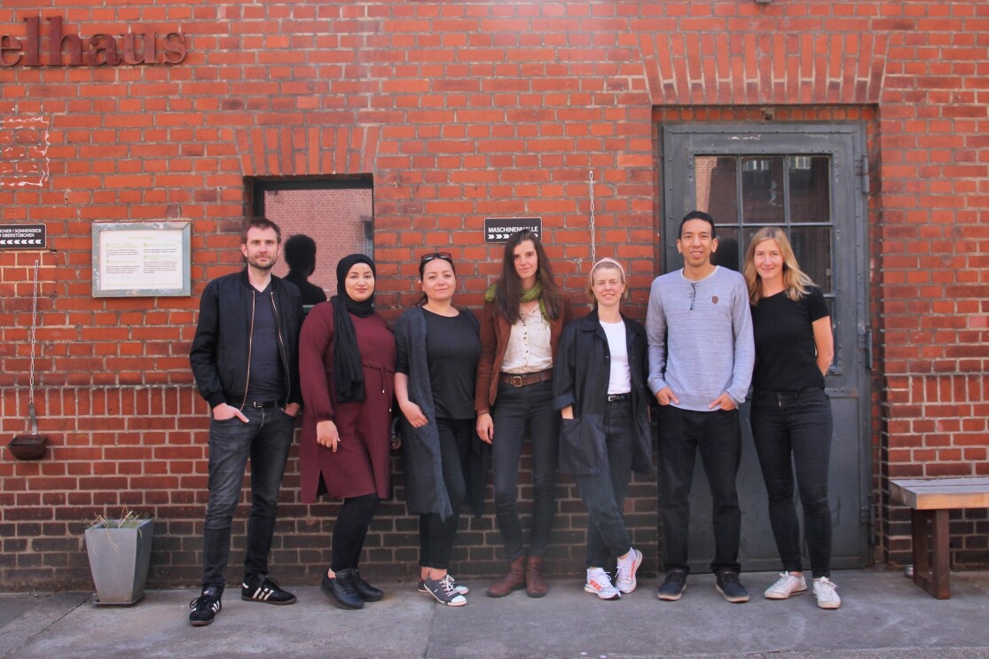 Teamfoto von Triaphon, bestehend aus fünf Frauen und zwei Männern, vor einer Backsteinwand.