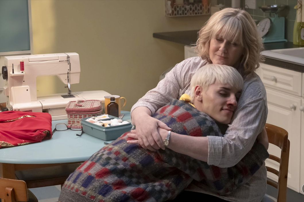 A woman hugging her son in her kitchen