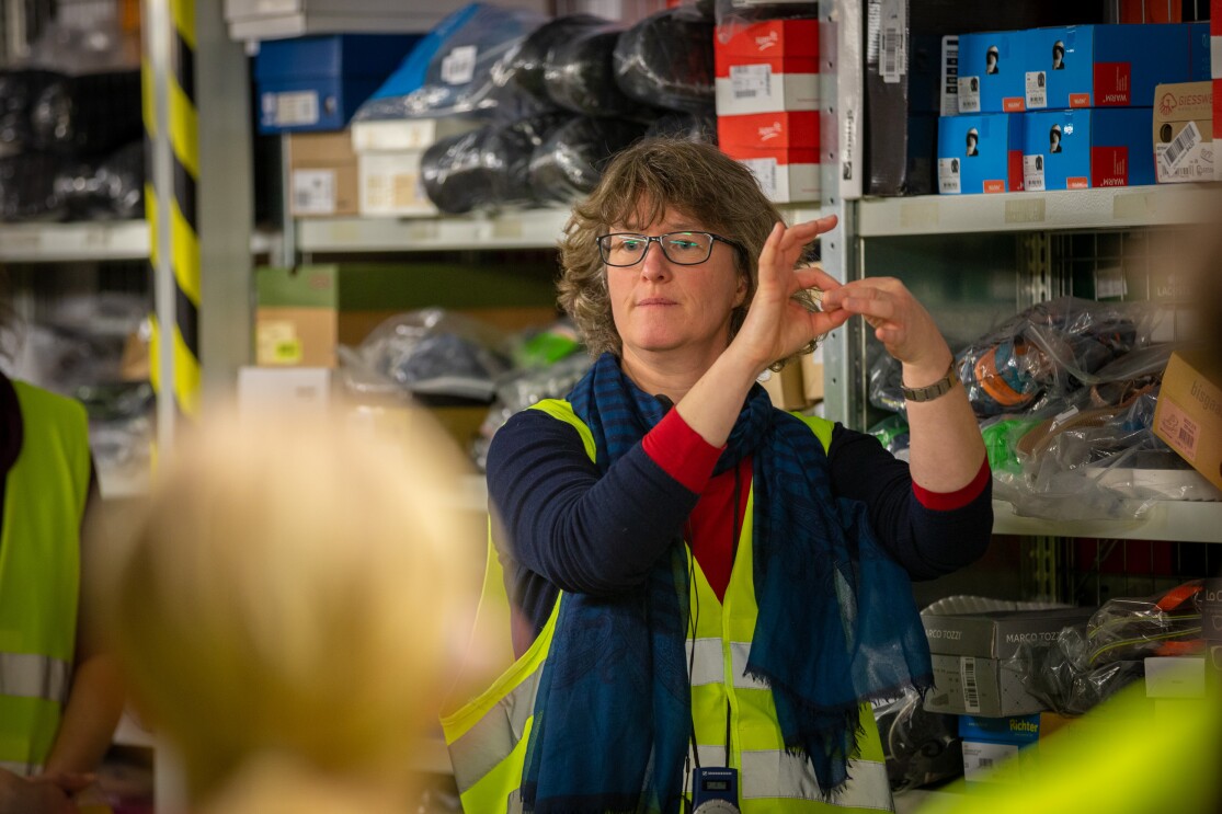 Eine Frau mit Brille übersetzt in Gebärdensprache.