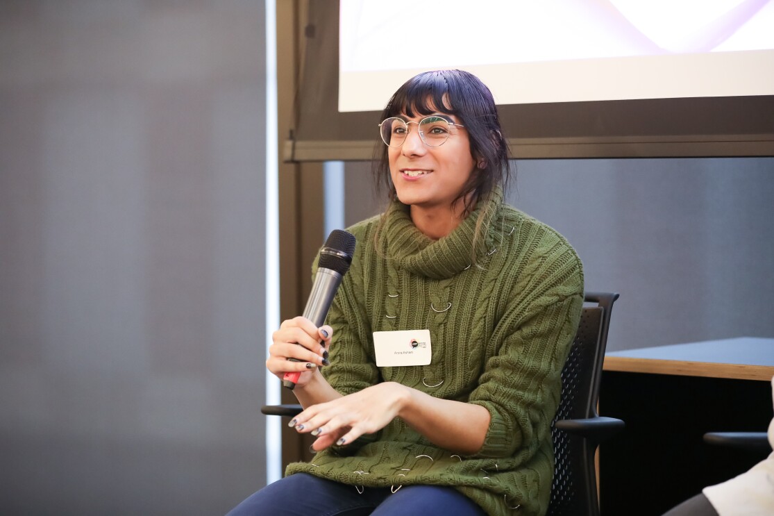 Arora Ashani is a developer for YOOX Net-a-Porter and co-founder of Non-Binary in Tech, holding a mic and giving a talk at the LGBT Leaders in STEM event.