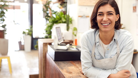 Portrait Of Smiling Female Sales Assistant Standing Behind Sales Desk Of Florists Store
