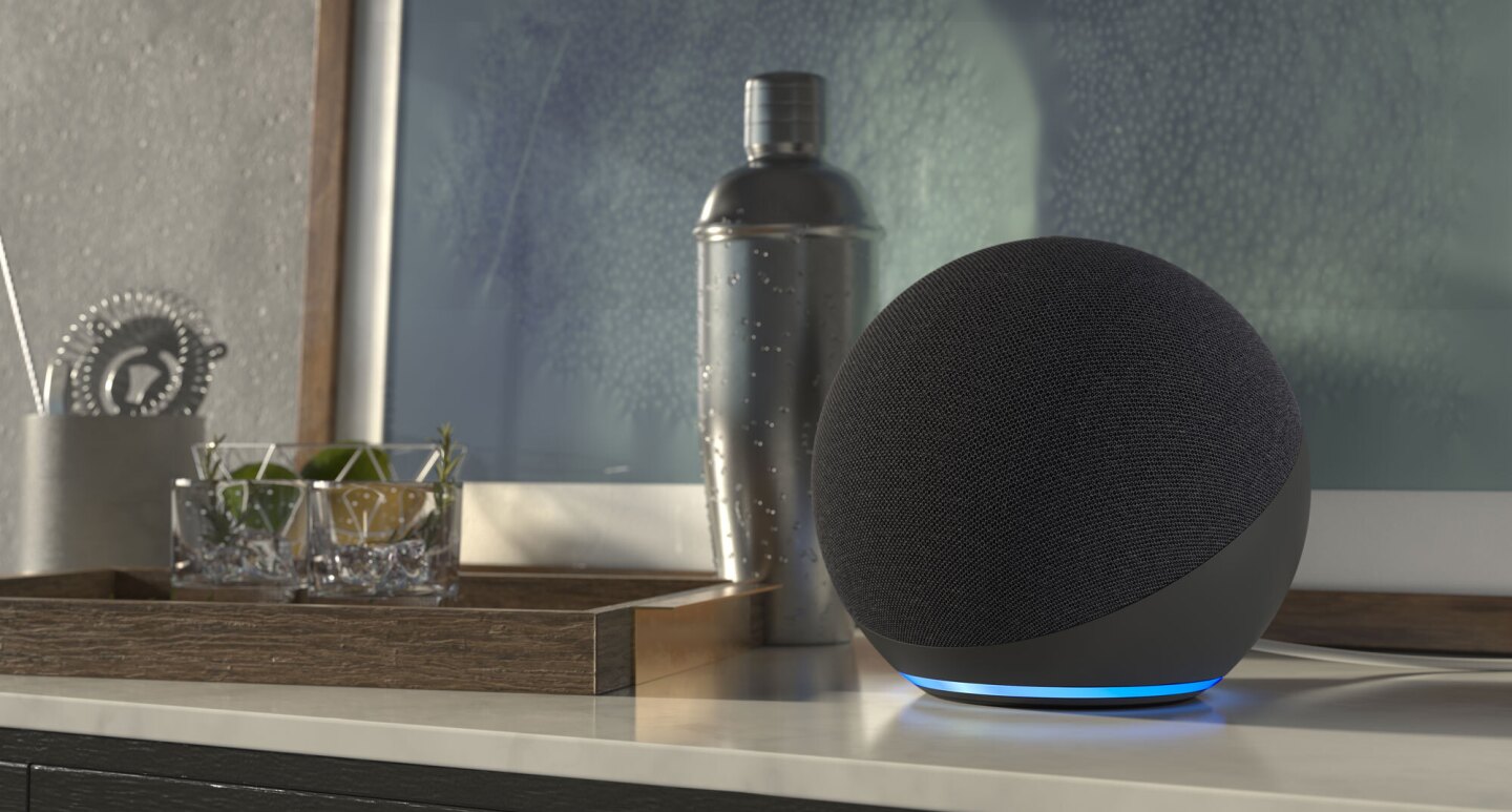 An Echo device sits on a table next to a cocktail shaker and two cocktail glasses.