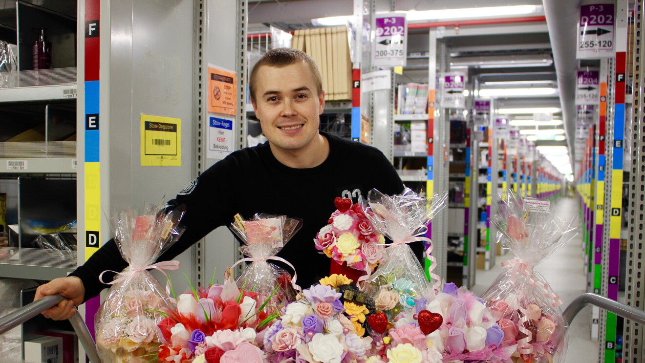 Juraj steht im Logistikzentrum, vor ihm eine bunte Palette an Seifensträußen