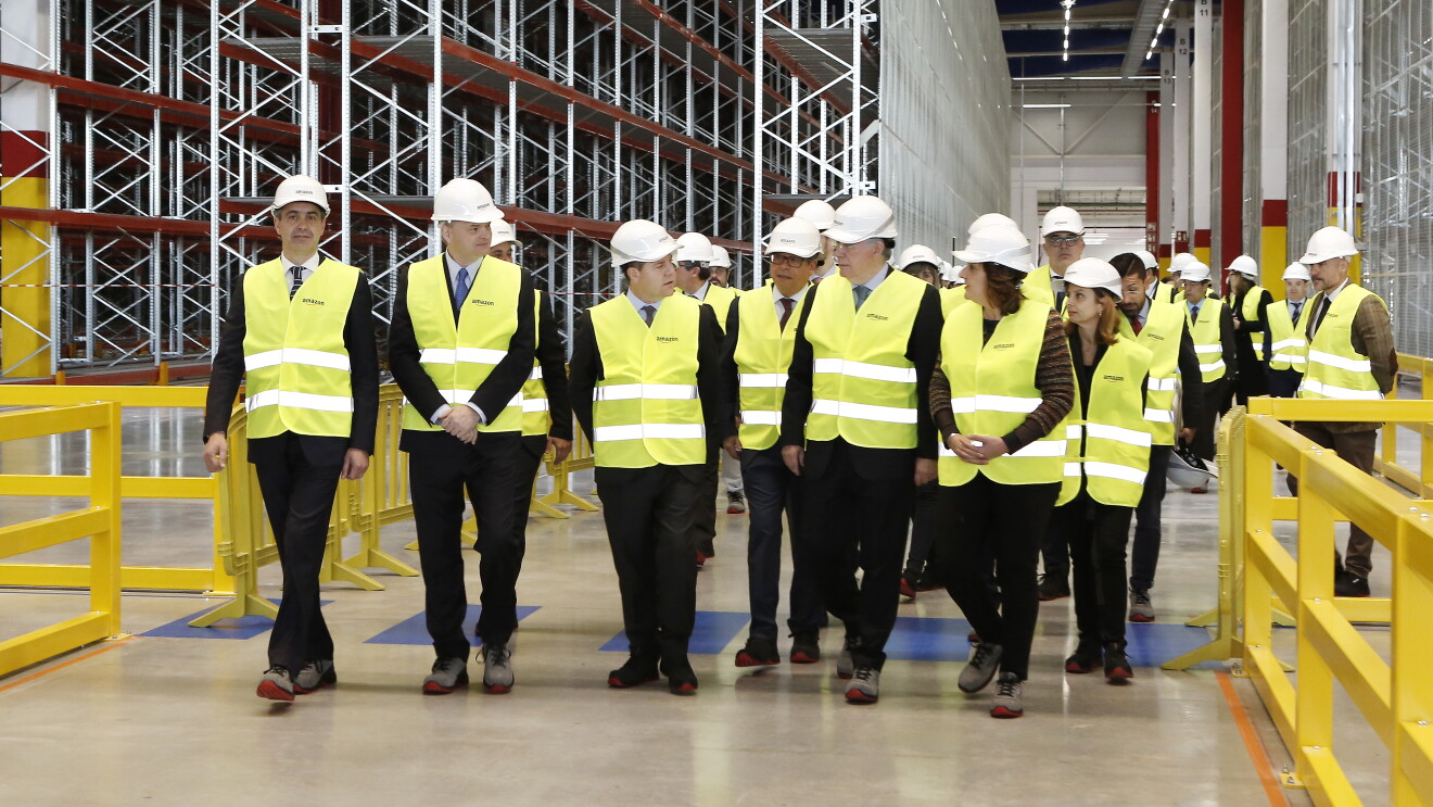Visita oficial de las autoridades locales al centro logístico de Illescas. Aparecen todos vestidos con el chaleco amarillo, las botas de seguridad y los cascos. Al fondo las estanterías vacías. A destacar: el director regional de Operaciones en España e Italia de Amazon, Fred Pattje, Nacho Ferreiro, Responsable del centro, el alcalde de Illescas, José Manuel Tofiño, y el presidente de Castilla-La Mancha, Emiliano García-Page.